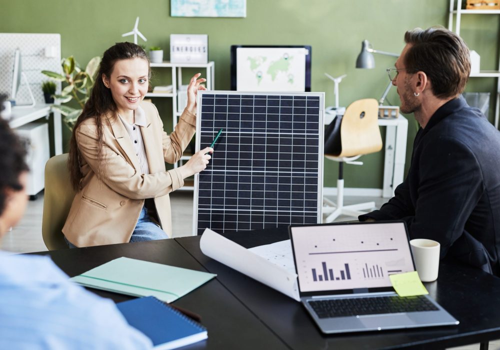 Young woman presenting solar panel to her colleagues during business meeting at office